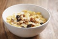 Closeup photo of corn flakes with fruits and nuts in white bowl on wood table Royalty Free Stock Photo