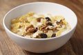 Closeup photo of corn flakes with fruits and nuts in white bowl on wood table Royalty Free Stock Photo