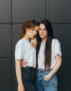 Closeup photo of a couple of attractive girls on black background wearing casual clothes and posing on camera with serious face. Royalty Free Stock Photo