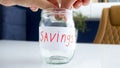 Closeup photo of couple putting coin in glass jar with family money savings Royalty Free Stock Photo