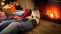 Closeup image of couple wearing woolen socks relaxing by the burning fireplace on Christmas eve