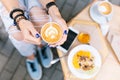 Closeup photo of cup of coffee with drawing in hands of young girl sitting outdoor. She wears jeans, blue sneakers, blu Royalty Free Stock Photo