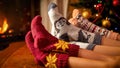 Closeup image of family in warm knitted socks lying next to fireplace and Christmas tree