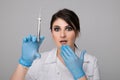 Closeup photo of female dentist holding oral syringe isolated over the grey backgrownd.