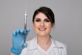 Closeup photo of female dentist holding oral syringe isolated over the grey backgrownd.