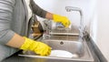 Closeup photo of female hands in yellow rubber gloves washing dishes Royalty Free Stock Photo