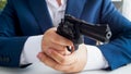 Closeup photo fo businessman in suit sitting in armchair and aiming with revolver