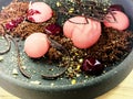Closeup photo of a fragment of a ceramic plate, with a pink dessert in the form of a heart and balls with chocolate