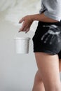 A closeup photo of a girl soiled with white putty holding a bucket against a background of plaster walls.