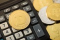 Closeup photo of gold dogecoin on calculator and coins with cryptocurrency symbols