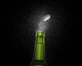 Closeup photo of an green beer bottle splashing beer drops on a black background. Beer cap flying on top of the bottle Royalty Free Stock Photo