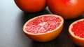 Closeup photo - half of pink grapefruit on dark working board, more citrus fruits in background Royalty Free Stock Photo