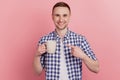 Closeup photo of handsome young man happy positive smile point finge mug coffee promo advice isolated pastel background