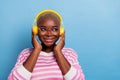 Closeup photo of happy young girl listening audio book holding headphones looking empty space isolated on blue color Royalty Free Stock Photo