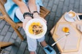 Closeup photo of healthy breakfast in hands of young girl sitting outdoor. She wears jeans, blue sneakers, blue na Royalty Free Stock Photo