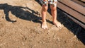 Closeup image of little boy in shorts with wet feet standing on sandy sea beach Royalty Free Stock Photo
