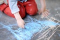 Closeup photo of little kid boy drawing with colored chalk on asphalt. Royalty Free Stock Photo