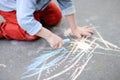 Closeup photo of little kid boy drawing with colored chalk on asphalt. Royalty Free Stock Photo