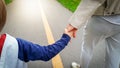 Closeup image of little 3 years old toddler boy holding his mother by hand and walking in park on road Royalty Free Stock Photo