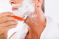 Closeup photo of a man with towel shaving himself with a razor Royalty Free Stock Photo