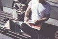 Closeup photo man wearing white tshirt sitting city park and writing notebook. Studying at the University, preparation Royalty Free Stock Photo