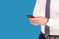 Closeup photo of men`s hands holding mobile smart phone, touching screen, typing, studio shot isolated on blue background Royalty Free Stock Photo