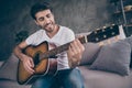 Closeup photo of mixed race guy sitting sofa hold acoustic instrumental guitar playing new written song sound love his