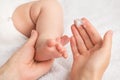 Closeup photo of mother`s hands holding newborn`s leg and applying cream on  white blanket background Royalty Free Stock Photo