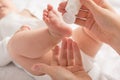 Closeup photo of newborn baby`s legs feet and mother`s hands holding white cream tube on isolated white background Royalty Free Stock Photo