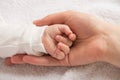 Closeup photo of newborn baby`s tiny hand in mother`s palm on isolated white textile background Royalty Free Stock Photo