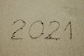 Closeup photo of 2021 numbers written on sand and footprints on sea beach. Concept of New Year, Christmas and travel on Royalty Free Stock Photo