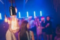 Closeup photo of old-fashioned light bulb making miracle atmosphere party crowd best friends on dance floor blurry focus