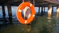 Closeup image of orange life saving ring hanging on wooden pier at sea beach Royalty Free Stock Photo