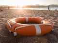 Closeup photo of orange plastic ring for saving drowning people on the sea lying on beach Royalty Free Stock Photo