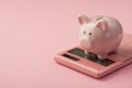 Closeup photo of piggy bank on pink calculator isolated pink background with copyspace