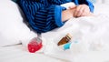 Closeup image of pills, throat sore and nasal spray in bed of sick woman