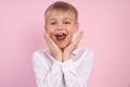 Closeup photo portrait of nice dreamy suprised amazed boy touching cheeks looking at camera isolated over pink background Royalty Free Stock Photo