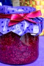 Closeup photo, raspberry jam-jar decorated with ribbon, craft paper