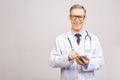 Closeup photo of senior man doctor standing isolated on grey background, using mobile phone Royalty Free Stock Photo