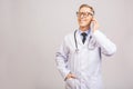 Closeup photo of senior man doctor standing isolated on grey background, using mobile phone Royalty Free Stock Photo