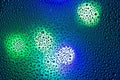 Closeup photo of shiny small circles of water drops on wet dark blue window with city lights Royalty Free Stock Photo