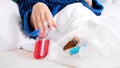 Closeup image of sick woman lying in bed under blanket and holding lots of medicines and sprays Royalty Free Stock Photo