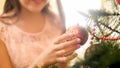 Closeup photo of smiling young woman holding red bauble hanging on Christmas tree
