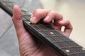 A closeup photo of the left hand fingers of a guitarist playing an acoustic guitar