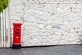 Closeup photo of tiny model British postbox against a stone wall