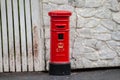 Closeup photo of tiny model British postbox against a stone wall