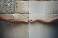Closeup photo of two hands holding each other in front of stone wall. Concept of Israeli-Palestinian conflict Royalty Free Stock Photo