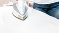 Closeup photo of white electric iron on cotton fabric Royalty Free Stock Photo