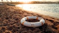 Closeup image of white plastic life saving ring lying on the sandy sea beach against beutiful sunset over the water Royalty Free Stock Photo