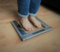 Closeup photo of woman feet standing on weight sacle over the hardwood floor Royalty Free Stock Photo